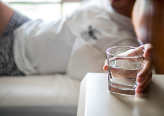 Obraz premium Hand of man holding a clear glass of water for drinking on bed in the Morning