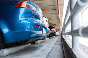 Naklejka premium Closeup blue cars parked in indoor parking building with steel rails, the concept of safety car.