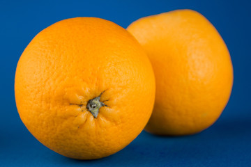 two orange oranges lying on a blue background