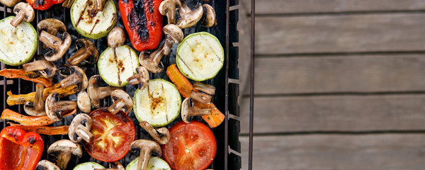  Healthy food preparing outdoors on summer or spring picnic. Grilled vegetables on grill on coals. Barbecue picnic on a meadow