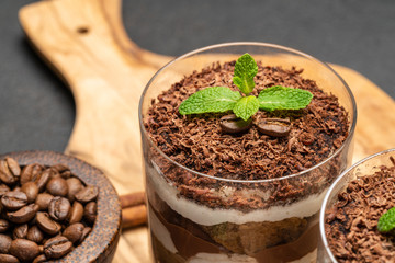 Classic tiramisu dessert in a glass on dark concrete background