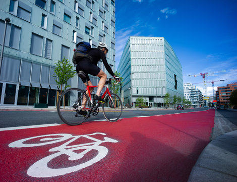 Cyclist in a symbol-marked, red bicycle lane in an urban area. Oslo, Norway.