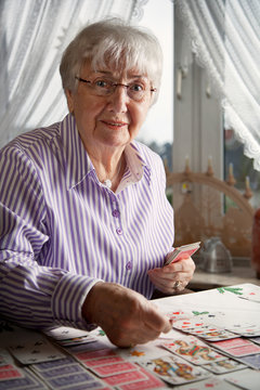 Senior Lady Playing Solitaire Cards At Home