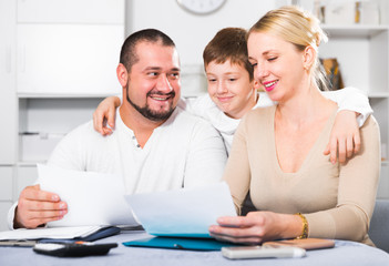Happy parents with son looking at documents