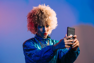 Cool looking young black woman taking selfie in studio setting