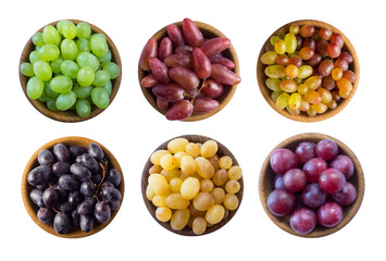 Grapes in a wooden bowl isolated on white background. Yellow, blue, pink and green grapes on white background. Grapes isolated on white. Vegetarian or healthy eating. Top view.