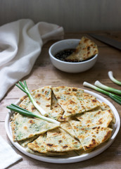Homemade appetizing scallion pancakes and a bunch of green onions. Rustic style.