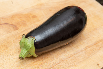 An organic, fresh and ripe aubergine on a wooden chopping board