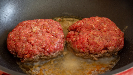 greasy burgers cooking in non stick pan