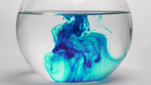 Spreading of dark blue chemical reagent into glass flask with pure transparent liquid. Close-up of chemical reaction in flask. Laboratory testing. Isolated, on white background