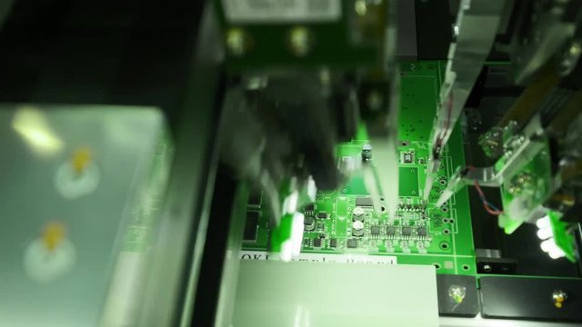 Production of electronic circuit boards. The latest innovative production of computer technology. The machine on the production line installs microchips on the microcircuit. Macro close-up
