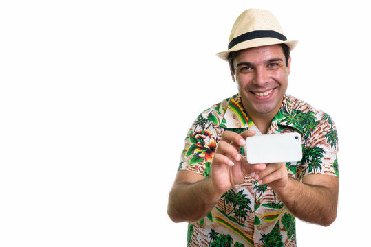 Studio shot of young happy Persian tourist man smiling while tak