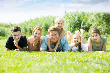 Glad man and woman with four kids lying in park