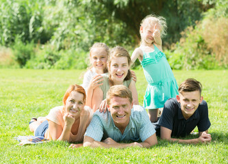 Fototapeta premium Young man and woman with kids lying in park