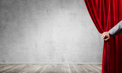 Concrete wall behind drapery curtain and hand opening it