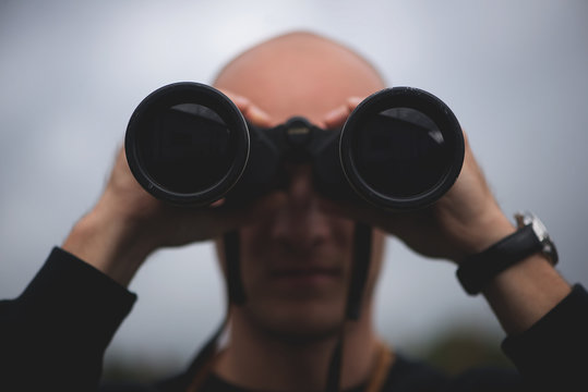Man looking through binoculars outdoors, close-up - stock photo