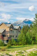 Beautiful exterior of newly built luxury home. Yard with green grass and mountain background.
