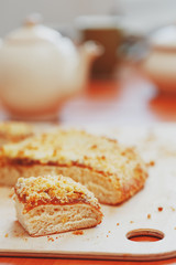 Sweet sand tart with apricot jam. Cut into pieces, lying on a board with a kettle in the background