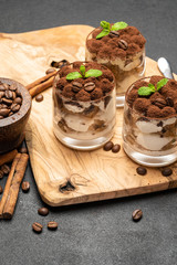 Classic tiramisu dessert in a glass on dark concrete background