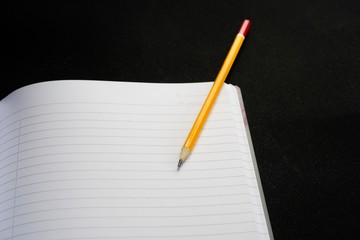 image of a notebooks and pencil on black background, close-up, selective focus