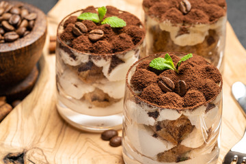Classic tiramisu dessert in a glass on dark concrete background