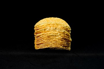 Delicious and crisp potato chips, isolated against black background, selective focus
