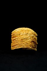 Delicious and crisp potato chips, isolated against black background, selective focus