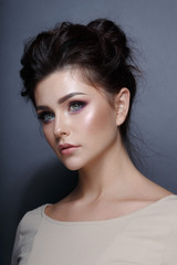 Profile portrait of a sensual young woman, hairstyle and perfect make-up, isolated on a grey background. Vertical view.