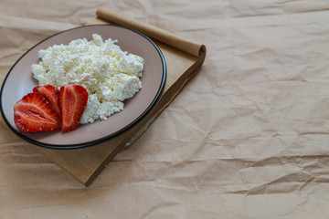 cottage cheese and strawberries in a plate on a paper background