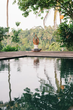 Female Yoga Practitioner Doing Asana by Pool in Tropics From Beh