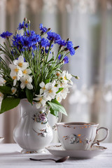 Fototapeta na wymiar On the table is a cup of tea and a bouquet of wild flowers in a vase
