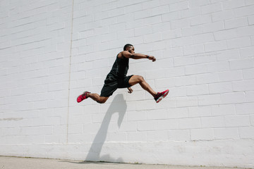 Fit athlete practicing sprints and jumps in a parking lot