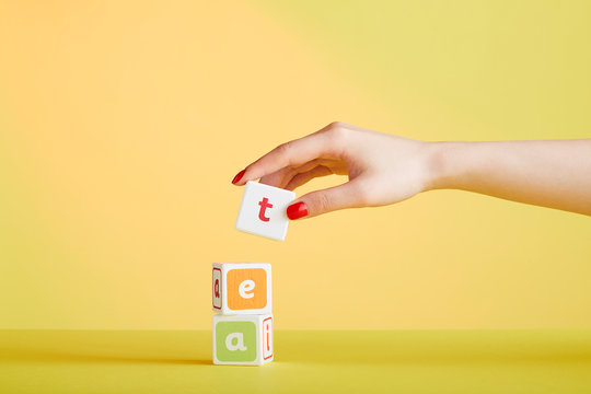 Woman's hand holds blocks spelling the word 'tea'