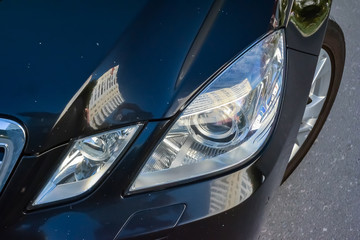 Close-up on the hood and fender of the car in black with white dots in the form of chips from stones and rubble that fly off the road. Repair scratches and defects in the body repair workshop.
