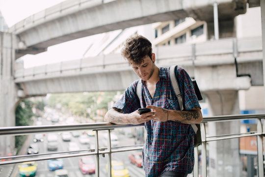 Young alternative man using a mobile phone in the city