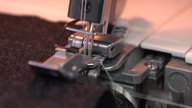 Industrial 4-Thread Overlock Machine. Fabric serging. Sewing With a Serger. Close up stitches in slow motion. Overlocking with cutters. Overedge Foot