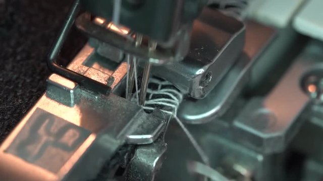 4-thread Serger slow motion. Overlock sewing machines  are used in industry for edging, hemming and seaming a fabrics. Overlocking, overedging, merrowing, serging. Close up overedge foot and stitches