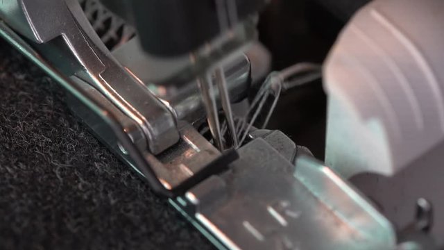 Overlock Sewing Machine. Close up stitches in slow motion. An overlock is a kind of stitch that sews over the edge of cloth for edging, hemming, or seaming