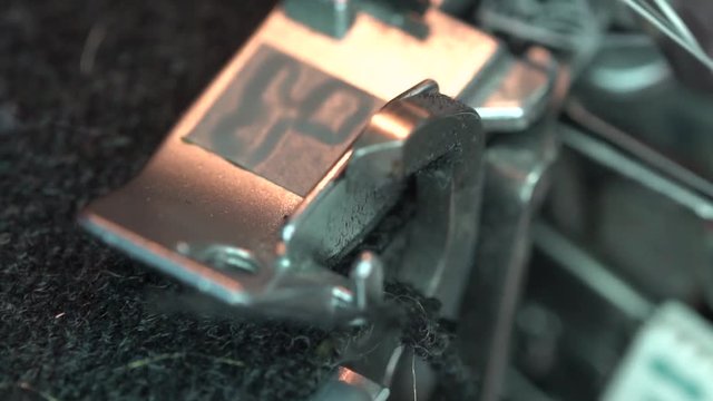 Overlock foot and cutter close up, slow motion. An serger sewing machine cuts the edges of the cloth. Garment Factory
