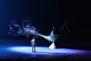Concept picture of a businessman looking at Aladdin lamp with glitter smoke, asking for a wish