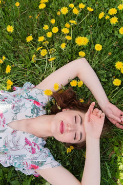 Woman lying in the grass, surrounded by dandelions