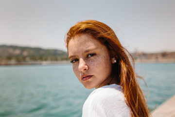 Portrait of redhead young woman with freckles standing outdoors