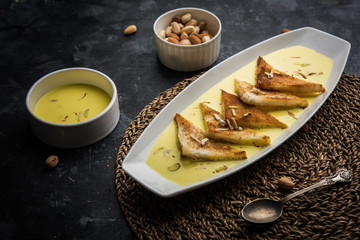 shahi tukra/tukda or Double ka meetha is a bread pudding Indian sweet of fried bread slices soaked in rabid or sweet saffron milk garnished with dry fruits, selective focus