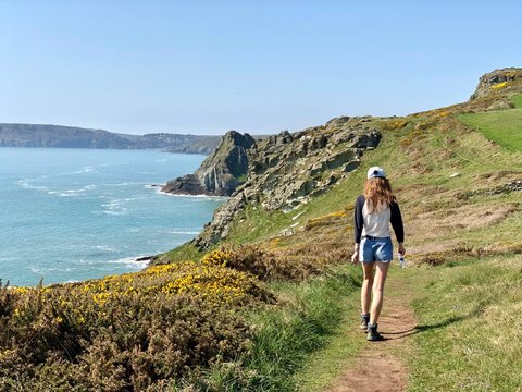 Beautiful Devon coastline with green rolling hills and farmland with a young woman in the foreground