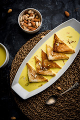 shahi tukra/tukda or Double ka meetha is a bread pudding Indian sweet of fried bread slices soaked in rabid or sweet saffron milk garnished with dry fruits, selective focus