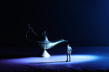 Concept picture of a businessman looking at Aladdin lamp asking for a wish