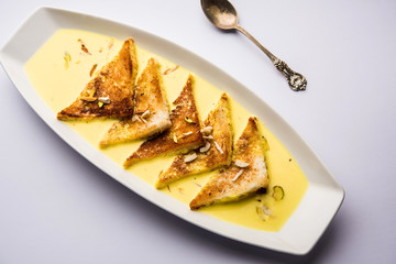 shahi tukra/tukda or Double ka meetha is a bread pudding Indian sweet of fried bread slices soaked in rabid or sweet saffron milk garnished with dry fruits, selective focus