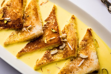 shahi tukra/tukda or Double ka meetha is a bread pudding Indian sweet of fried bread slices soaked in rabid or sweet saffron milk garnished with dry fruits, selective focus