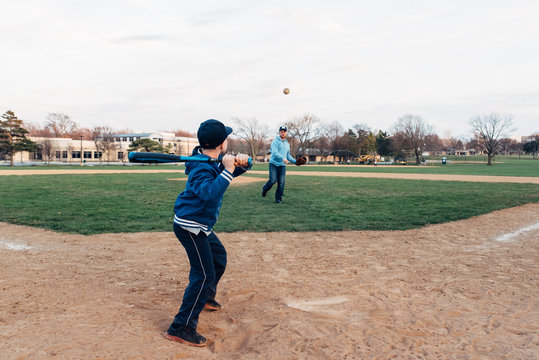 Father throwing a ball to his son who's batting