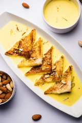 shahi tukra/tukda or Double ka meetha is a bread pudding Indian sweet of fried bread slices soaked in rabid or sweet saffron milk garnished with dry fruits, selective focus